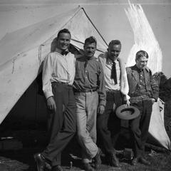 Four men standing outside tent