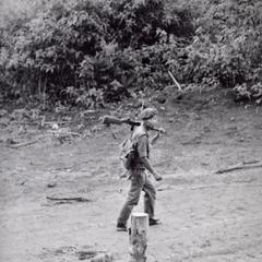 A local soldier walks along the road in Houei Kong carrying his rifle in Attapu Province