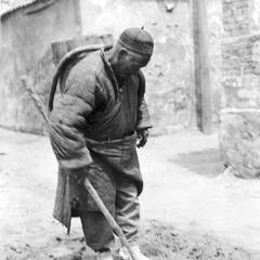Elderly Chinese man collecting manure.