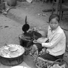 Lao woman selling griddle cakes at morning market