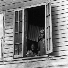 Men Looking Out Window of Wood House in Freetown