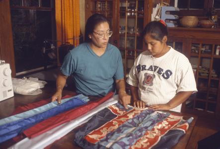 Elena Greendeer teaches ribbon skirt making to her daughter Verna