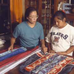 Elena Greendeer teaches ribbon skirt making to her daughter Verna