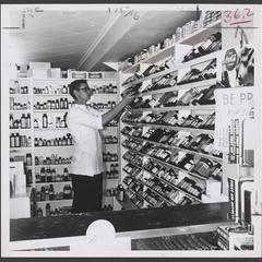 A man stands next to slanted shelves in a pharmacy
