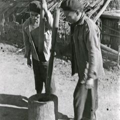 Two men in a Black Lahu (Lahu Na) village pound rice in Houa Khong Province