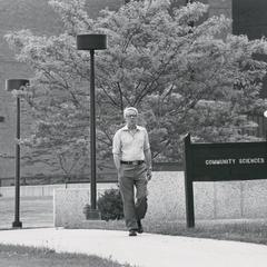 Professor James Clifton walking on campus in front of Library Learning Center