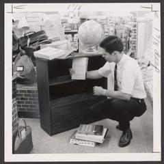 A young man selects school supplies from a drugstore display