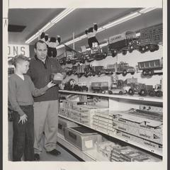 A salesman assists a young shopper in the toy department