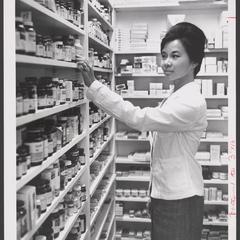 A young pharmacist examines the stock on shelves