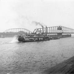 Sternwheel side view of the Kit Carson pushing a barge on the Mississippi River