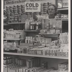 A clerk adjusts a sign at a display of cold remedies