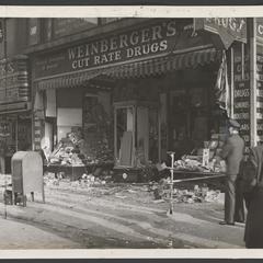 Two men look at front of bombed drugstore