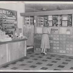 A customer speaks to pharmacy staff at the prescription counter