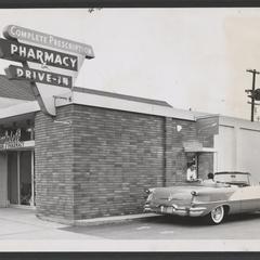 A convertible car's driver is serviced at a pharmacy drive-in window