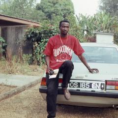 Bodunde Motoni leaning against car