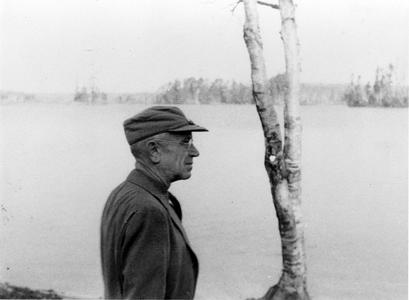 Aldo Leopold in cap and coat along the river