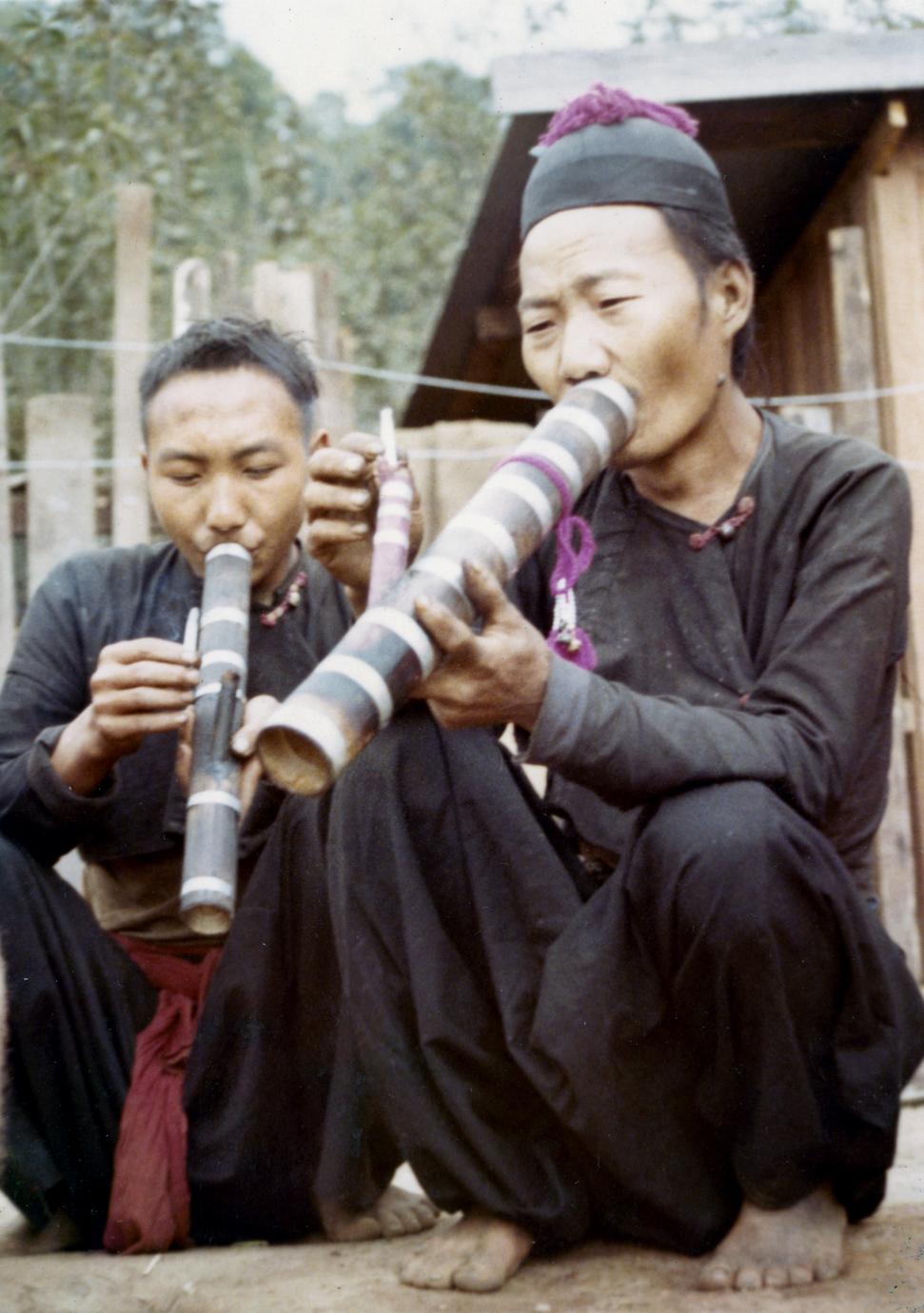 Two Blue Hmong (Hmong Njua) men smoking water pipes in northern Thailand