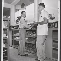 Two men stand at a counter in a pharmacy