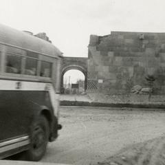 "A bus passing a building that was destroyed during the war"
