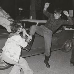 Man kicks a woman holding a flag at a Neo-Nazi event
