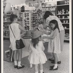 A woman and three young girls try on hats and sunglasses