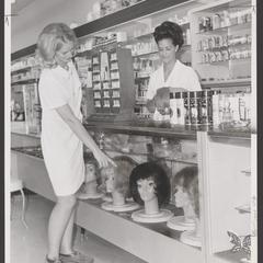 A customer points to a selection of wigs in a drugstore display