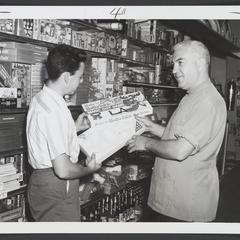 A pharmacist shows a youth a game in a drugstore game department