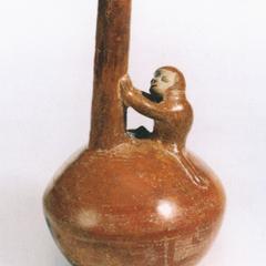 Bottle with long spout held by monkey.