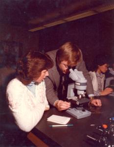 Instructor and student looking through microscopes