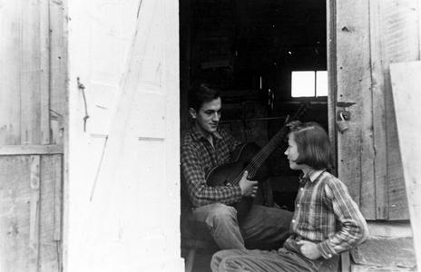 Carl Leopold with guitar and Estella in shack doorway