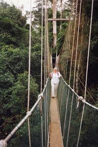 Woman walking across rope bridge in Kakum National Park
