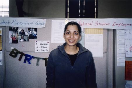 Female student poses in front of a bulletin board