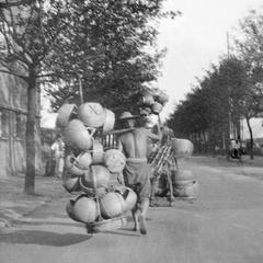 Man carrying baskets with a shoulder pole.