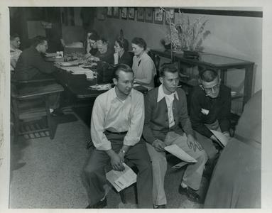 Sigma Tau Gamma members and others working at a table and watching a demonstration