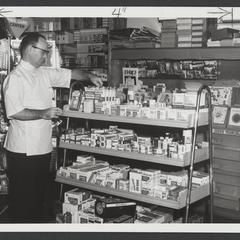 "Pharmacist checks his first aid display to see that it is fully stocked"