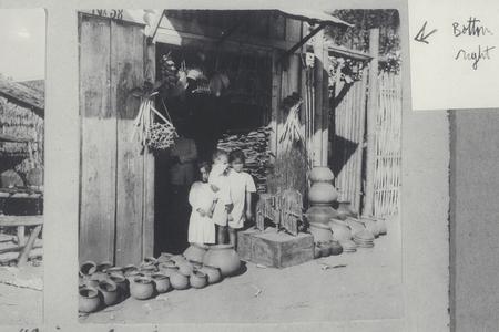 Three Filipino children standing in front of store among pots