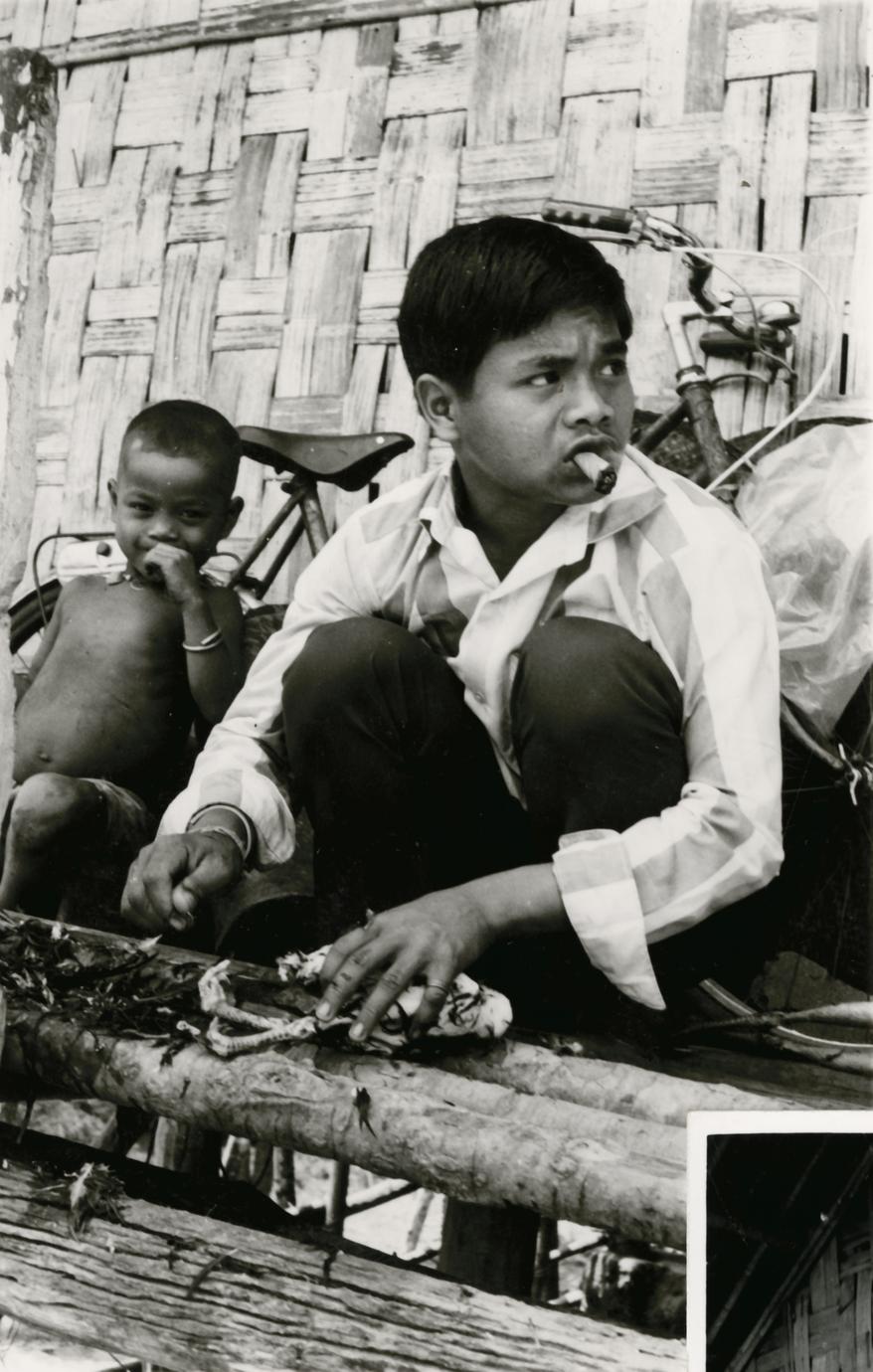 A Nyaheun boy plucks a chicken on his porch in Attapu Province