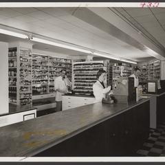 Pharmacy staff work behind the prescription counter of a drugstore
