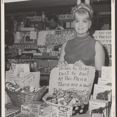 A salesclerk displays handwritten signs in a drugstore