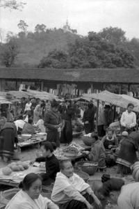 Morning market with Phu Si Buddhist monument shrine visible on hill in background