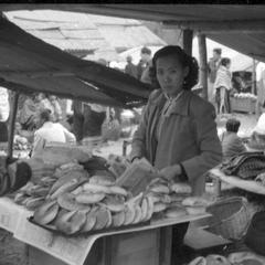 Chinese woman selling baked rolls, French style, to male customer