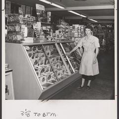 A saleswoman stands at a display of cigars in a drugstore