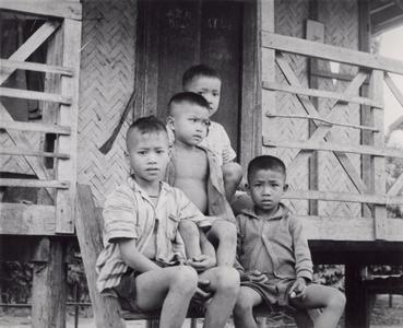 Four Laven boys are seated on the steps of a village house in Houei Kong Cluster in Attapu Province