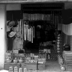 Chinese shop displaying parasols, hats, jackets, kettles, enameled ware for carrying food