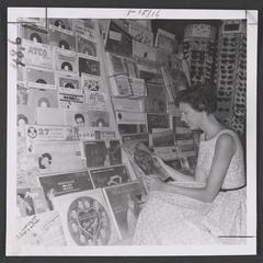 Young woman looks at a record in drugstore's record section