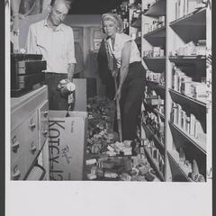A man and a woman clean up debris in drugstore