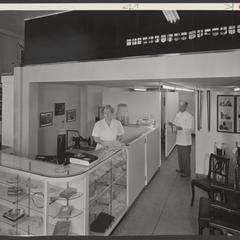 A pharmacist and saleswoman staff a surgical appliance counter
