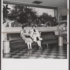 Two women sit in a waiting area while their prescriptions are being filled