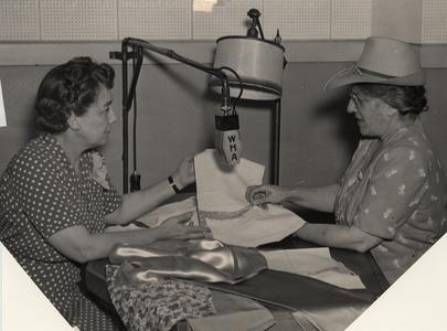 Aline Hazard with guest, handling cloth before microphone