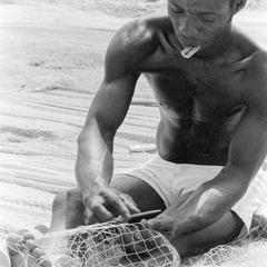 Man with Razor Blade Mending Net for Ocean Fishing